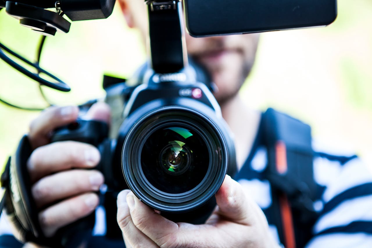 services-03 A close-up shot of a cameraman filming, focusing on the camera lens and equipment.
